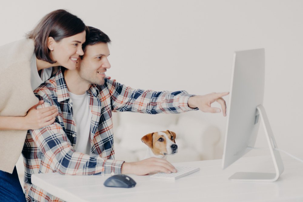 Beitragsbild: zwei zufriedene Menschen, am Computer, mit Hund abgebildet