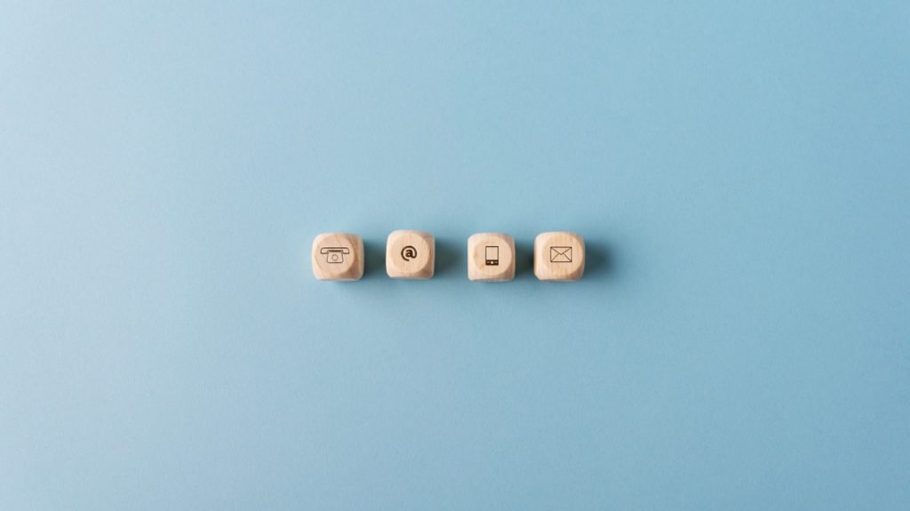 Beitragsbild: Kontakt und Kommunikation Icons, aus Holzwürfeln, mit blauem Hintergrund