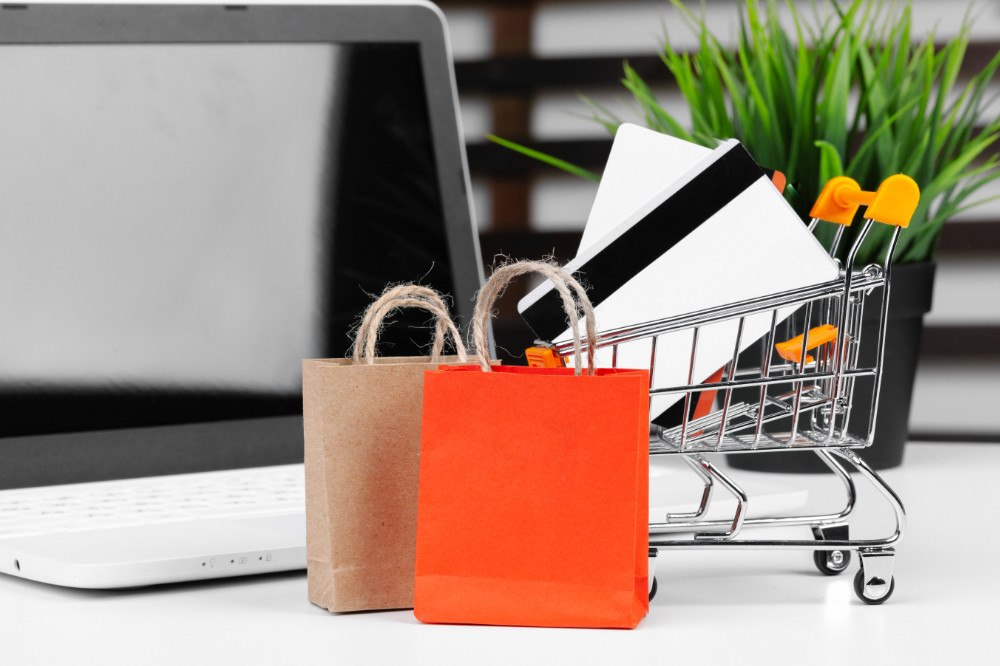 Online Shopping Konzept, Einkaufswagen, Laptop auf Schreibtisch
