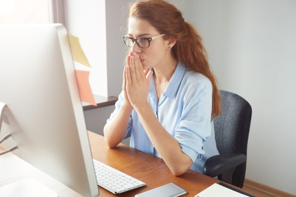 Porträt einer jungen Frau, nachdenklich, sitzt vor dem PC
